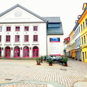 ein großes weißes Gebäude mit roten Fenstern auf einer Straße in der Unterkunft Ferienwohnung 1 Christiansdorf Freiberg in Freiberg