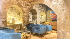 a living room with blue chairs and a stone wall at PipaD'oro by YoursPorto in Porto