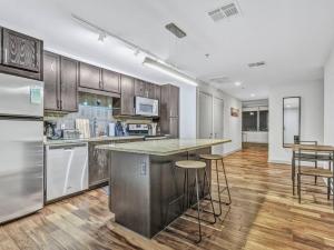a large kitchen with a counter and stools in it at Luxury Apt W/Parking CityView|Pool| Gym|PoolTable in Dallas