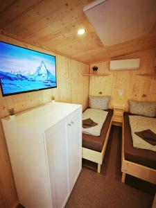 a small room with two beds and a tv on the wall at Tiny Guesthouse Euerbach in Euerbach