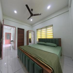 a bedroom with a green bed and a ceiling fan at Philip's Signature Suites in Cochin