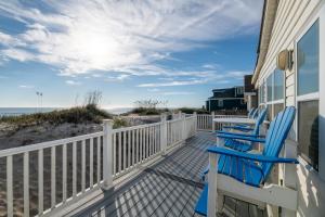 a porch with two blue chairs and the beach at Aqua Moon - Kitty Hawk MP 3, Oceanfront, Family Friendly, Hot Tub in Kitty Hawk