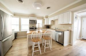a kitchen with white cabinets and two bar stools at Aqua Moon - Kitty Hawk MP 3, Oceanfront, Family Friendly, Hot Tub in Kitty Hawk