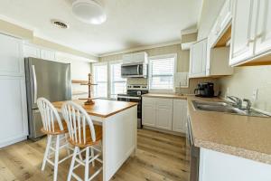 a kitchen with white cabinets and a counter with two stools at Aqua Moon - Kitty Hawk MP 3, Oceanfront, Family Friendly, Hot Tub in Kitty Hawk +38 photos