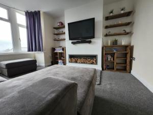 a living room with a tv and a fireplace at Bank End Cottage in Almondbury