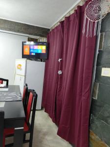 a red curtain in a kitchen with a table and a television at La tranquera ll in Trapiche