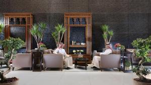 two men sitting in chairs in a room with plants at Sedra Al Alami Jeddah in Jeddah
