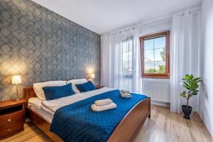 a bedroom with a bed with blue sheets and a window at Apartment Katry with Tatry View & Balcony in Veľká Lomnica +16 photos