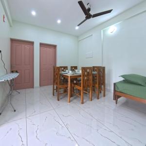 a dining room with a table and chairs and a ceiling fan at Philip's Signature Suites in Cochin