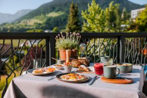 a table with plates of food on a balcony at Hotel Der Waldhof in Vollan