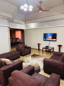 a living room with couches and a flat screen tv at C&B House MV in Accra