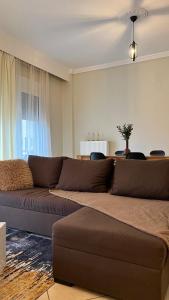 a living room with a brown couch in front of a window at Flat30 - Cosy apartment in Park of Kipseli- Xanthi in Xanthi +28 photos