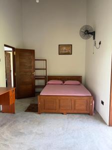 a bedroom with a bed with pink sheets and a door at Gurugoda Riverside Villa in Ruwanwella