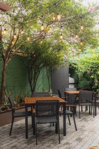 a patio with wooden tables and chairs under a tree at Pousada Du Valle in Embu