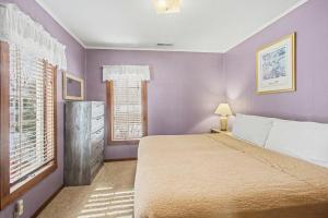 a purple bedroom with a bed and a window at A Shore Thing in Douglas