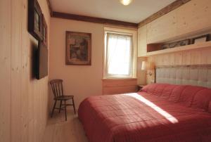 a bedroom with a red bed and a chair at Brand new beautiful ground floor flat in Cortina dʼAmpezzo