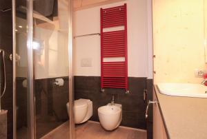 a bathroom with a toilet and a sink and a red shutter at Brand new beautiful ground floor flat in Cortina dʼAmpezzo