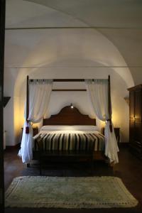 a bedroom with a canopy bed with curtains and a rug at Hotel Rural Las Grullas in Villanueva del Fresno