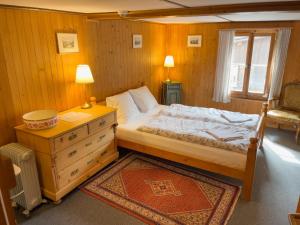 a bedroom with a bed with a dresser and a window at Pension Gimmelwald in Gimmelwald +17 photos