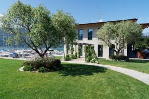 a building with trees in front of a yard at Lago Dorato Marina Lodge - Lakefront in Colico