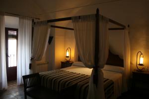 a bedroom with a canopy bed with curtains and a chair at Hotel Rural Las Grullas in Villanueva del Fresno