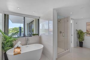 a white bathroom with a tub and a shower at Waterfront Luxe Condo - Close to beach in Hallandale Beach