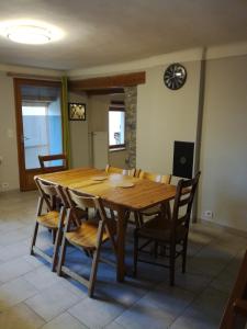 a wooden dining room table with chairs and a clock on the wall at Maison à Briançon in Briançon