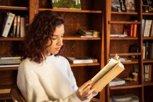 a woman sitting in a chair reading a book at PinusVillas Private Jacuzzi & Phyto-Sauna in Zheleznitsa +98 photos