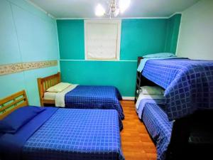 two beds in a room with blue walls at Central House in Punta Arenas