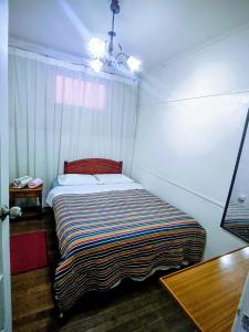 a small bedroom with a bed with a striped blanket at Central House in Punta Arenas