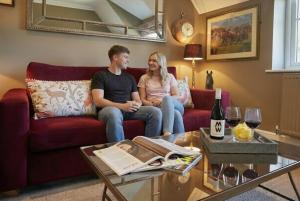 a man and a woman sitting on a red couch at Boutique Bedrooms in Thornham