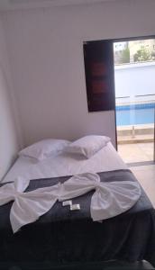 a bed with white sheets and pillows in a room at Pousada Pérola dos Corais Maceió in Maceió