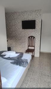 a bedroom with a bed and a chair and a television at Pousada Pérola dos Corais Maceió in Maceió