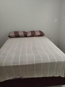 a bed with a white mattress and a pillow on it at Recanto da LM in Foz do Iguaçu
