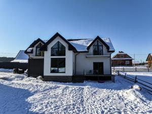 a house with snow on the ground in front of it at Апартаменти Rest Hill in Vorokhta