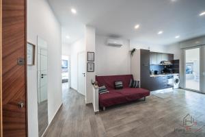 a living room with a red couch and a kitchen at Panorama Blu - Spiaggia 7min - Terrazza - WiFi in Celle Ligure