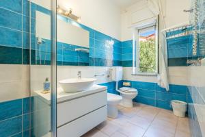 a blue tiled bathroom with a sink and a toilet at A.I.R. Hotel Gabbiano in Isola Rossa +122 photos