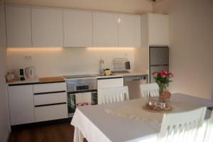 a kitchen with white cabinets and a table with flowers on it at Quinta das Candeias - Casa da Bé in Arcos de Valdevez