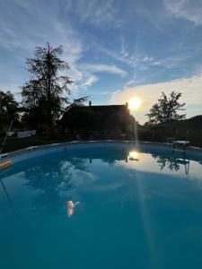 a large swimming pool with the sun setting in the background at Villa Bernoux in Sagy