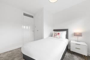 a white bedroom with a white bed and a nightstand at Large 5 Bedroom House Perfect For Group Stays - Free Parking - Near Glasgow - Perfect For Contractors in High Blantyre
