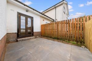 a patio in front of a wooden fence at Large 5 Bedroom House Perfect For Group Stays - Free Parking - Near Glasgow - Perfect For Contractors in High Blantyre