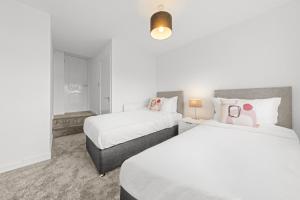 two beds in a hotel room with white at Large 5 Bedroom House Perfect For Group Stays - Free Parking - Near Glasgow - Perfect For Contractors in High Blantyre