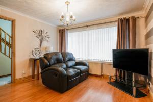 a living room with a leather chair and a television at Jake's House in Airdrie