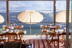 a restaurant with tables and umbrellas in front of a window at Casa do Rio - Douro Wine Hotel by Vallado in Vila Nova de Foz Coa