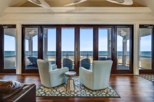 a living room with chairs and glass windows at Good Karma Retreat - Nags Head MP 15.5, Oceanfront, Elevator, Pool, Hot Tub, Pets OK, Flex Stays in Nags Head