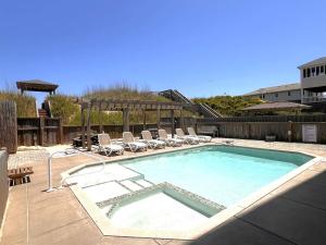 a large swimming pool with chairs and a swimming pool at Good Karma Retreat - Nags Head MP 15.5, Oceanfront, Elevator, Pool, Hot Tub, Pets OK, Flex Stays in Nags Head