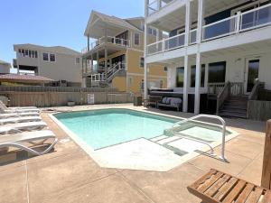 a swimming pool in front of a building at Good Karma Retreat - Nags Head MP 15.5, Oceanfront, Elevator, Pool, Hot Tub, Pets OK, Flex Stays in Nags Head