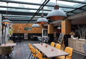 a restaurant with tables and chairs and pendant lights at Hotel Brasserie de Klok in Zutendaal