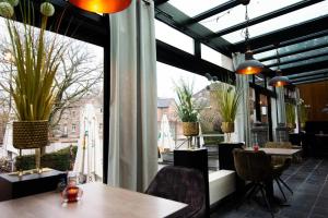 a restaurant with tables and chairs and a large window at Hotel Brasserie de Klok in Zutendaal