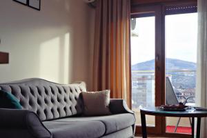 a living room with a couch and a large window at Apartman Jaman - Novi Pazar in Novi Pazar